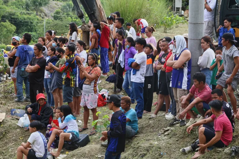 Relatives and others wait for updates after a huge mound of garbage collapsed at a waste segregation facility in Binaliw, Cebu city on Friday, Jan. 9, 2026. (AP Photo/Jacqueline Hernandez)